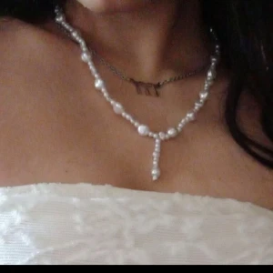 Pärlhalsband med droppformad detalj - Säljer ett snyggt halsband med oregelbundna vita pärlor och en droppformad hängande detalj framtill. Kedjan är i silverfärg som man kan justera som ni ser hur lång man vill ha den. (Kedjan är inte äkta silver)💕