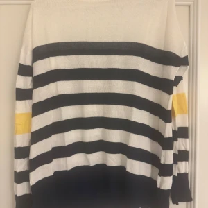 Randig stickad tröja Brave Soul M - Säljer en stickad tröja från Brave Soul i storlek M. Tröjan är vit med svarta och gula ränder, har långärmad design och rund hals. Perfekt för dig som gillar klassiska mönster med en färgklick på ärmen. Superenkel att matcha med jeans eller kjol.