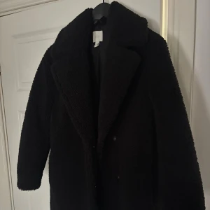 Svart teddyjacka från H&M - Nyskick! Svart teddyjacka från H&M med bred krage och knappar framtill. Jackan har en lös passform. 