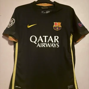 FC Barcelona Neymar Jr 11 bortatröja - Snygg svart FC Barcelona bortatröja från Nike med Neymar Jr och nummer 11 på ryggen. Tröjan har gula detaljer, klubbmärke, Champions League-patch och Qatar Airways-tryck. Tillverkad i Dri-FIT-material som andas. Perfekt för dig som älskar fotboll och Barca.