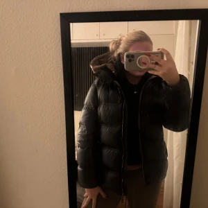 Svart pufferjacka från Massimo Dutti - Säljer en svart pufferjacka från Massimo Dutti med glansig finish och huva. Jackan har två sidofickor med dragkedja och en snygg quiltad design. Perfekt för kalla dagar och har en riktigt chill vibe. Passar dig som gillar stilren och enkel look. Väldigt eftertraktad och populär💕