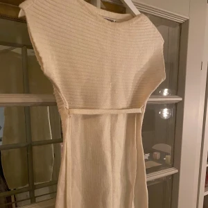 Vit stickad kortklänning - Supersnygg vit/cremefärgad stickad klänning från Terranova i storlek XS. Modellen är kort med ribbad struktur upptill