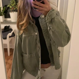 Grön jeansjacka från Zara - Säljer en ljusgrön oversized jeansjacka med stora fickor framtill och knäppning med silvriga knappar. Jackan har en avslappnad passform och långa ärmar, perfekt att slänga på sig över en t-shirt. Materialet är kraftigt och ger en cool vintagekänsla.