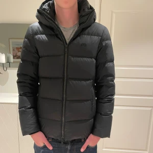 J Lindeberg jacka - Hej! Säljer en oerhört snygg svart pufferjacka från J.Lindeberg med huva och diskret logga på bröstet. Jackan har en clean look, raka linjer och dragkedja framtill. Perfekt för kalla dagar och har en schysst passform som funkar till allt! Storleken är S men sitter som en S/M. Skicket är enligt mig mycket bra (9/10). Nypriset är 4000kr+. Vid fler frågor är det bara att höra av er!