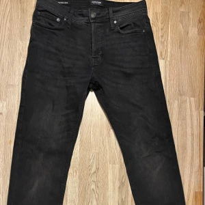 Svarta jeans från Jack & Jones, Mike,  29/32 - Svarta jeans från Jack & Jones med klassisk femficksdesign och snygga detaljer på bakfickorna. Jeansen har en rak passform och är tillverkade i mjukt denimtyg som sitter skönt hela dagen. Perfekt för dig som gillar stilrena och enkla jeans.