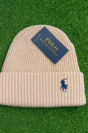 Beige ribbad mössa från Polo Ralph Lauren - Snygg beige ribbad mössa från Polo Ralph Lauren med klassisk blå broderad logga framtill. Tillverkad i mjuk kashmir som känns lyxig och varm. Perfekt accessoar för att höja din vinterstil.