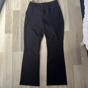 Svarta kostymbyxor från BikBok - Svarta kostymbyxor från BikBok i klassisk modell med raka ben och pressveck. Byxorna har hällor för bälte, två fickor bak och stängs med dragkedja, knapp och hake. Perfekta för en clean och stilren look. Byxorna har en låg midja. Pris kan diskuteras.