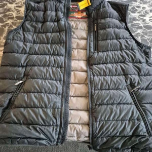 Svart dunväst från Parajumpers - Snygg svart dunväst från Parajumpers med quiltad design och dragkedjor framtill. Västen är superlätt och har flera praktiska fickor med dragkedja. Perfekt för lager-på-lager och ger en sportig vibe till din outfit.