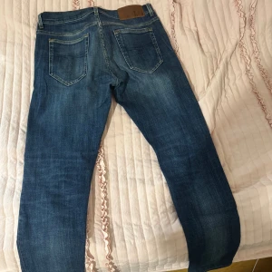 Slim fit blå jeans med slitningar - Snygga slim fit jeans från Mezzo, tillverkade i Italien. Modellen har en klassisk femficksdesign, blå tvätt med slitningar och trasiga detaljer vid knäna för en cool look. Passar dig som gillar en smalare siluett och streetstyle.