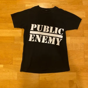 Svart Supreme x Undercover t-shirt - Svart t-shirt med stor vit text 'PUBLIC ENEMY' på framsidan och grafiskt tryck med texten 'BLOW YOUR MIND.' samt Undercover Supreme-logga på baksidan. Klassisk passform och cool streetwear vibe, perfekt för dig som gillar statement-plagg.             Det en jätte bra rep.