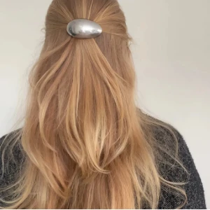 Silverfärgad hårklämma i metall 2st - Snygg oval hårklämma i blank silverfärgad metall med enkel och stilren design. Perfekt för att sätta upp håret på ett coolt sätt och ge frisyren en modern touch. Klämman har ett smidigt spänne på baksidan som håller håret på plats hela dagen.