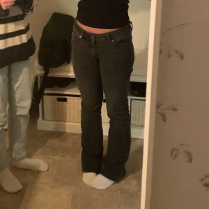 Svarta bootcut jeans från Junkyard - Snygga svarta jeans från Junkyard med bootcut passform och låg midja. Klassisk femficksdesign, svarta sömmar och mjukt stretchigt denimtyg som sitter skönt. Perfekt för dig som gillar en lite retro vibe och vill ha jeans med lite utsvängda ben.