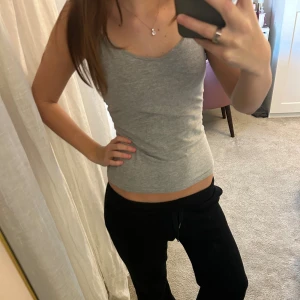 Grå linnetopp med smala axelband - Säljer en enkel och stilren grå linnetopp med smala axelband. Toppen har en tight passform och är tillverkad i mjukt bomullsmaterial som känns skönt mot huden. Perfekt att matcha med jeans eller mjukisbyxor för en chill look.