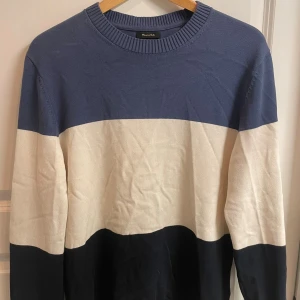 Randig tröja från Massimo Dutti - Snygg randig tröja från Massimo Dutti i storlek M. Tröjan har breda blockränder i marinblått, vitt och svart, rund hals och långa ärmar. Materialet är mjuk bomull som känns skönt mot huden. Perfekt för dig som gillar stilrena och klassiska plagg.
