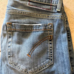 Blå skinny jeans från Dondup, stl 33 - Snygga blå jeans från Dondup i storlek 33. Modellen har klassisk femficksdesign, smal passform och coola detaljer som broderad bakficka och metallknapp med logga. Jeansen är gjorda i mjukt denimtyg med lätt tvättad look och kontrastsömmar.