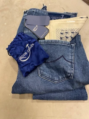Jacob Cohen blå jeans - Säljer ett par sjukt snygga blå jeans från Jacob Cohen med klassisk femficksdesign och snygg slitning. Jeansen har råa, fransiga benslut och kommer med allt og. Perfekta för dig som gillar exklusiva detaljer och den populära ”Grish-stilen”. Använda typ 3 gånger så dom är i princip nya! Riktigt bra pris men inte helt spikat så kom dm för frågor bud eller fler bilder!