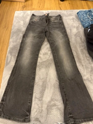Grå bootcut jeans Gina Tricot - Säljer ett par grå jeans från Gina Tricot med bootcut-modell. Jeansen har klassisk femficksdesign, dragkedja och knapp i kopparfärg. Materialet är mjukt denim i bomull och passformen är normal med lätt utsvängda ben.