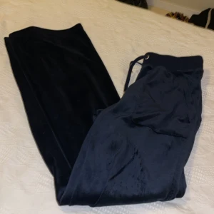 Mörkblå mjukisbyxor från Bindelid XS i velour - Mörkblå mjukisbyxor från Bindelid i mjukt och glansigt material. Byxorna har bred resår i midjan med snörning och boot cut ben. Perfekta för chill dagar eller när du vill vara extra bekväm.