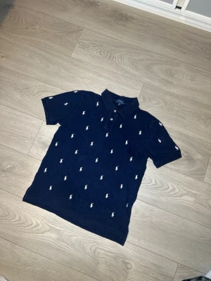 Ralph Lauren piké - Hej! Säljer nu denna Mörkblåa Ralph Lauren pikén. Kortärmad samt storlek XL, kvinnostorlek S/M i herr. Inga skador eller fläckar. Riktigt unik och snygg piké!  Skickar alltid inom 24h efter köp🤩 Frågor om mått eller annat? Hör av dig!