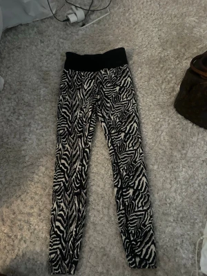 Zebramönstrade leggings från Stronger - Snygga leggings från Stronger med svartvitt zebramönster och bred svart midjeresår. Perfekta för dig som vill sticka ut på gymmet eller i vardagen. Stretchigt material som sitter skönt och följsamt.