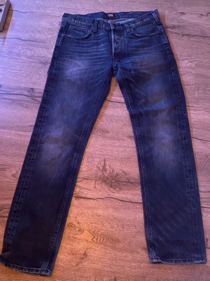 Mörkblå Lee jeans straight fit - Säljer ett par mörkblå jeans från Lee med klassisk femficksdesign och snygga slitningar framtill. Jeansen har raka ben och normal passform, tillverkade i slitstarkt denimtyg. Perfekta för dig som gillar en tidlös och clean look.