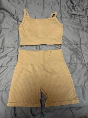 Beige ribbad träningsväst H&M Move - Säljer en beige ribbad träningsväst från H&M Move i storlek S. Västen har smala axelband och är croppad, Materialet är stretchigt och mjukt, 