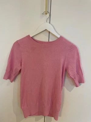 Rosa stickad tröja  - Söt rosa stickad topp från Kappahl i storlek XS, skulle säga att den passar S & M också. Modellen har rund halsringning, ribbade muddar vid ärmslut och nederkant samt korta ärmar. Perfekt nu inför snart våren. Den har endast använts fåtal gånger och har inge defekter.