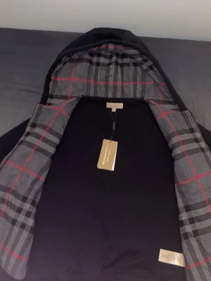 Burberry hoodie - Helt ny svart Burberry hoodie i svart med svarta mösnter. Aldrig använd och kommer med tag som synns på bilden. Storlek S. Pris går att diskutera.