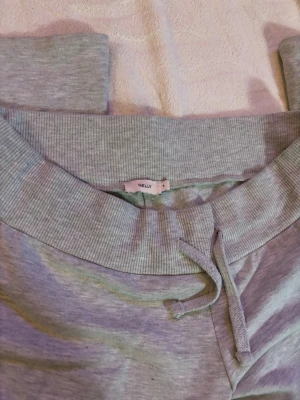 Grå mjukisbyxor från Nelly - Säljer ett par ljusgrå mjukisbyxor från Nelly med bootcut-modell. Byxorna har bred resår i midjan, snörning framtillu. Använd få gånger