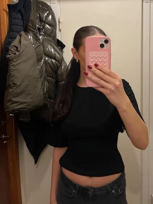 Nelly open back tie tee  - Säljer en svart croppad topp med korta ärmar och knytband i midjan. Endast använd fåtal gånger, storlek Xs.