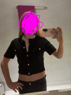 Svart kortärmad kofta med guldknappar  - Kortärmad svart kofta från Gina tricot, med guldknappar i st 146-152