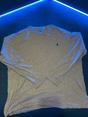 Grå långärmad tröja Polo Ralph Lauren - Säljer en stilren grå långärmad tröja från Polo Ralph Lauren i mjuk bomull. Klassisk passform med rund halsringning och den ikoniska lilla loggan broderad på bröstet. Perfekt till jeans eller chinos för en clean look. Fläckar kan finnas men går att tvätta 