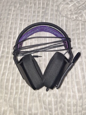 Logitech G335 Gaming Headset - Logitech G335 gamingheadset med kabel och mikrofon. Bekväma öronkuddar och justerbart huvudband i lila/blått. 3,5 mm anslutning, kompatibel med PC, konsol och mobil. Bra skick, inga synliga defekter eller större slitage.