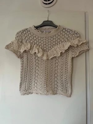 Beige stickad topp med volang Zara - Supersöt beige stickad topp från Zara med korta ärmar och rund hals.