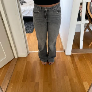 Gråa raka jeans från Zara - Säljer ett par gråa jeans från Zara i rak modell med normal passform. Jeansen har klassisk femficksdesign, hög midja och är tillverkade i bomull. Perfekta om du gillar en enkel och stilren look med lite vintage-vibe. Uppgångna i hälen.