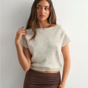 Beige stickad topp från Nelly - Superpopulär beige stickad topp från Nelly med bred halsringning och korta ärmar. Mjuk och fluffig känsla, perfekt till både jeans och kjol. Den är enkel, stilren och lätt att matcha. Storlek small. Aldrig använd pga den var lite stor på mig. 