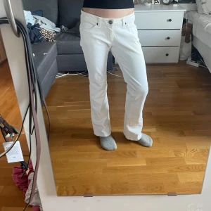 Vita bootcut jeans från Wrangler - Midjemått: 35,5cm Innerbensmått: 72cm Ytterbensmått: 91cm                                          Säljer ett par vita jeans från Wrangler med bootcut-modell. Byxorna har klassiska fem fickor, snygga detaljer på bakfickorna och stängs med dragkedja och knapp. Perfekta för dig som gillar en tidlös och clean look.