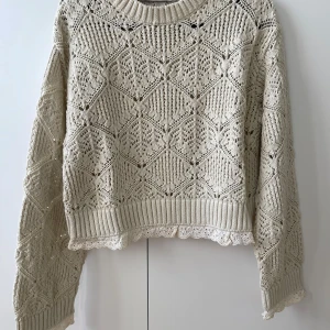 Beige stickad spetsdetaljerad tröja Zara - Superfin beige stickad tröja från Zara med unikt hålmönster och spetskant nertill och vid ärmslut. Tröjan har lång ärm, ribbade muddar och en lite croppad passform. Perfekt för lager-på-lager och ger en romantisk vibe till din outfit. Använd 2 gånger. 
