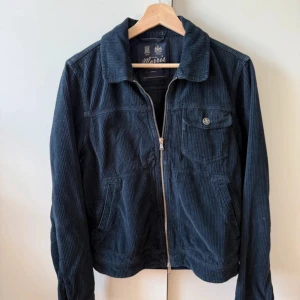 Morris mörkblå manchesterjacka S - Snygg mörkblå manchesterjacka från Morris i klassisk modell. Jackan har dragkedja framtill, bröstficka med knapp, två sidofickor och krage. Nypris 1199kr