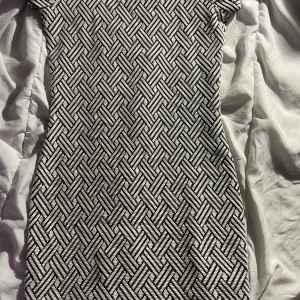 Mönstrad kortklänning från Mango - Säljer en snygg kortklänning från Mango med svartvitt grafiskt mönster. Klänningen har korta ärmar och en figurnära passform. Materialet är mjukt och stretchigt, perfekt för dig som gillar stilrena och moderna vibes.