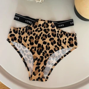 Underpants No°2 - Snygg bikiniunderdel med leopardmönster i beige och svart. Hög midja och breda svarta resårband med texten LOVE för en cool och trendig look. Perfekt för stranden eller poolen när du vill sticka ut.
