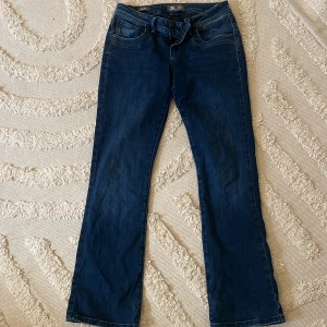 LTB Valerie bootcut jeans - Mörkblå jeans från LTB, modell Valerie, med låg midja och bootcut. Klassisk femficksdesign och snygg tvätt. Perfekta för dig som gillar en tidlös look med lite utsvängda ben. Materialet är mjukt och följsamt jeans.