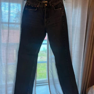 Levi's svarta straight jeans med slits - Svarta jeans från Levi's med klassisk femficksdesign, raka ben och hög midja. Jeansen har en snygg slits nertill på benen som ger en cool touch. Tillverkade i robust denim som sitter skönt och passar till många olika stilar. Lite urtvättade