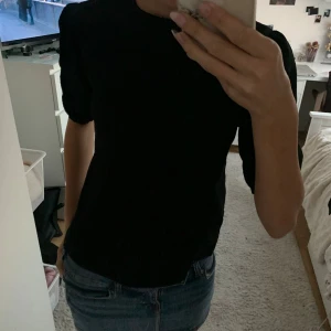 Svart blus med puffärm - Säljer en svart blus med puffiga ärmar och rund halsringning. Toppen har en rak passform och är tillverkad i ett mjukt tyg som känns skönt mot huden. Perfekt att styla med jeans eller kjol för en clean look. Xs/s