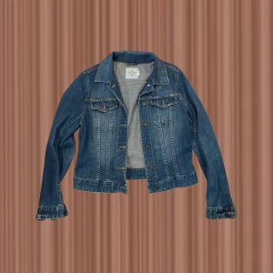 Blå jeansjacka från H&M  - Klassisk blå jeansjacka från H&M L.O.G.G. i storlek 44. Jackan har snygga bronsfärgade knappar framtill, två bröstfickor med lock och långärmade ärmar. Den är tillverkad i slitstarkt jeanstyg och har en tidlös, normal passform som funkar till allt.