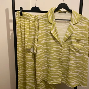 Zebramönstrad skjorta från Threadbare - Säljer en kortärmad skjorta från Threadbare i ljusgrönt och vitt zebramönster. Skjortan har klassisk krage, knäppning framtill och bröstficka. Materialet känns mjukt och svalt, perfekt för varmare dagar.