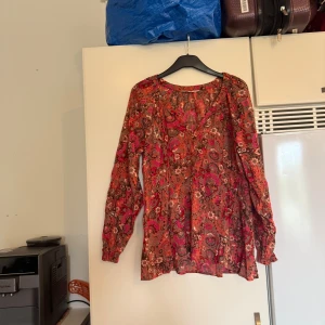 Mönstrad blus från Odd Molly - Säljer en färgstark blus från Odd Molly med v-ringning och långa ärmar. Blusen har ett detaljerat blommigt och paisleyinspirerat mönster i orange, rosa och brunt. Luftig passform och tunnt tyg, perfekt för dig som gillar boho-vibbar. Storlek 2 som enligt deras storleksguide motsvarar en storlek M. Mycket fint skick, jag hittar inga synliga anmärkningar eller defekter. 