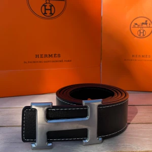 H Bälte Svart - Säljer ett svart bälte med ett silvrigt snyggt ”H” spänne. Bältet har en längd på 105 cm (storlek 42) och är Inte använt en enda gång, tveka inte att fråga! 💯👌