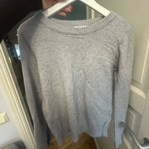 Ljusgrå stickad tröja från Vila XS - En enkel och stilren ljusgrå stickad tröja från Vila i storlek XS. Tröjan har rund halsringning, ribbade muddar och är långärmad. Perfekt för lager-på-lager under kyliga dagar. Liten defekt som framkommer på andra bilden