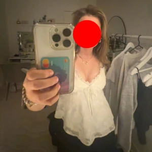 Vit spetslinnetopp med knyt - Säljer en söt vit linnetopp med spetsdetaljer och v-ringning. Toppen har tunna axelband, knyt framtill och en lätt volangkant nedtill. Perfekt för dig som gillar romantisk och feminin stil.